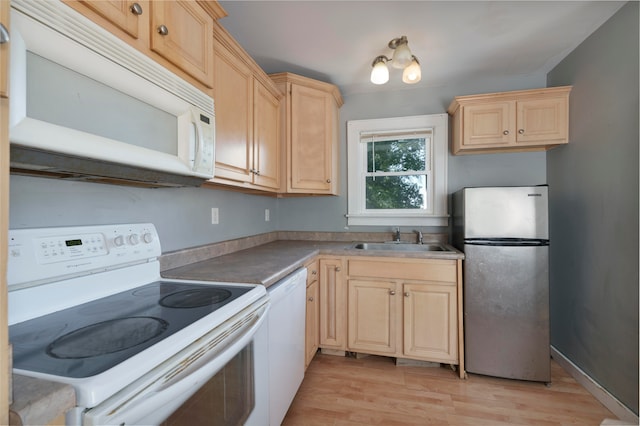 kitchen with sink, white appliances, light brown cabinets, and light hardwood / wood-style flooring