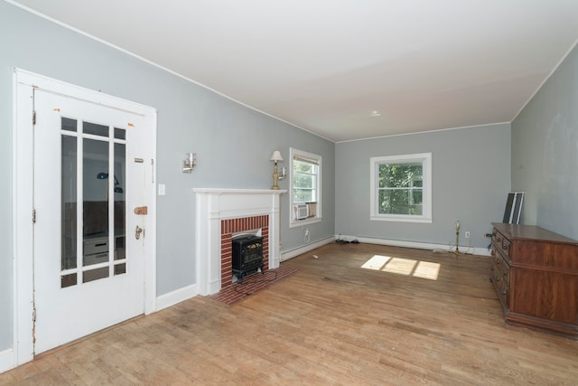 unfurnished living room featuring light wood-type flooring, crown molding, baseboard heating, and a fireplace