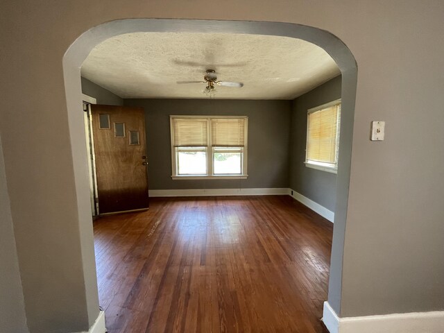 empty room with a textured ceiling, ceiling fan, and wood-type flooring