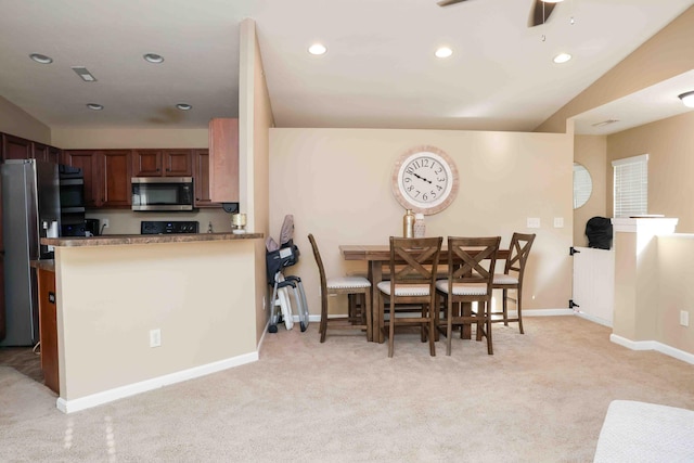 kitchen featuring stainless steel appliances, kitchen peninsula, light carpet, and lofted ceiling