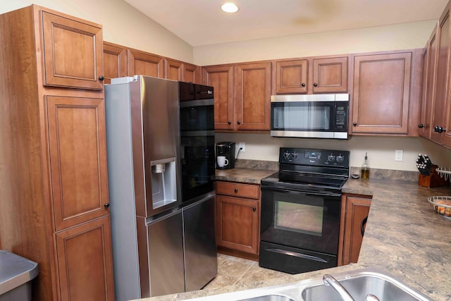 kitchen with appliances with stainless steel finishes, vaulted ceiling, and light tile patterned floors