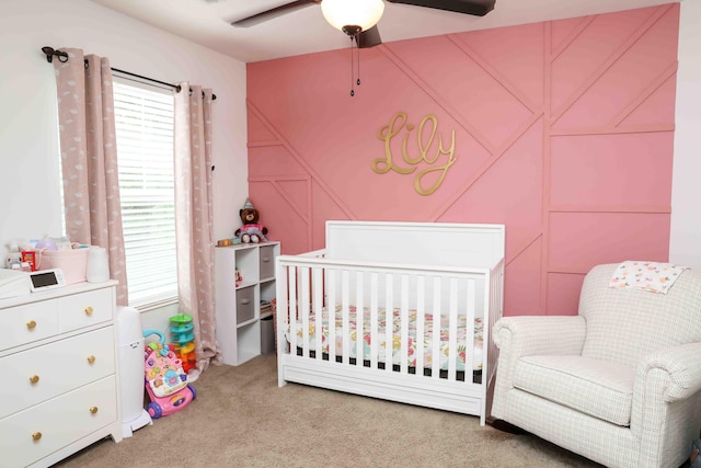 bedroom featuring carpet floors, a nursery area, and ceiling fan