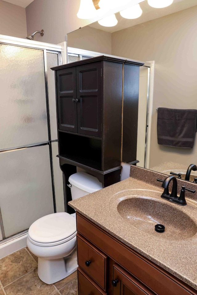 bathroom with a shower with shower door, toilet, vanity, and tile patterned floors