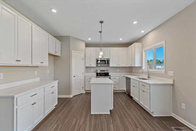 kitchen with white cabinetry, sink, stainless steel appliances, pendant lighting, and a kitchen island