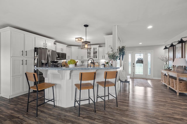 kitchen featuring stainless steel fridge with ice dispenser, glass insert cabinets, a kitchen breakfast bar, decorative light fixtures, and white cabinetry