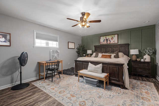 bedroom featuring dark wood-style floors, a decorative wall, and baseboards