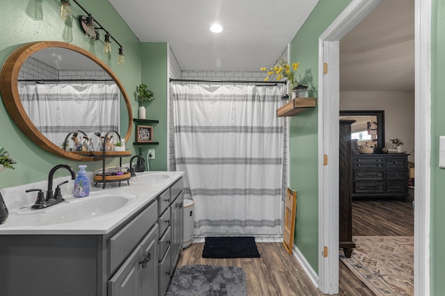 full bathroom featuring double vanity, a shower with curtain, a sink, and wood finished floors