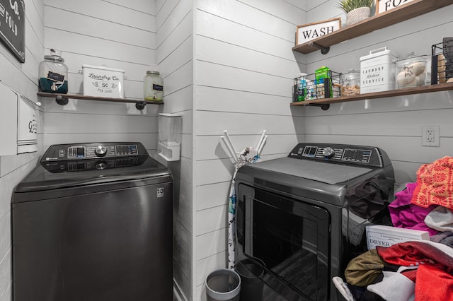 laundry room featuring laundry area, wood walls, and washing machine and dryer