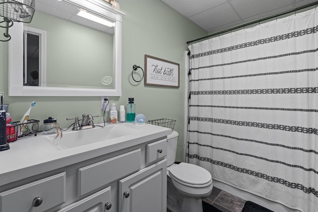 full bathroom with toilet, curtained shower, a drop ceiling, and vanity