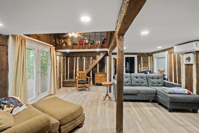 living room with light wood-type flooring, a wall mounted AC, and wood walls