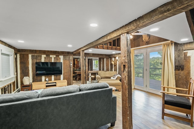 living room with beamed ceiling, wood-type flooring, and wood walls