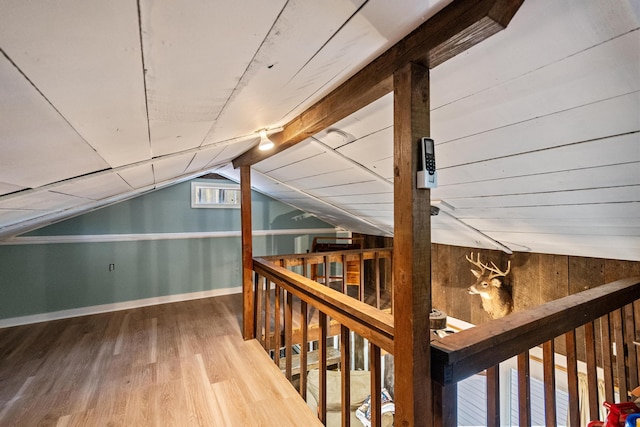 bonus room featuring vaulted ceiling, hardwood / wood-style floors, and wooden walls