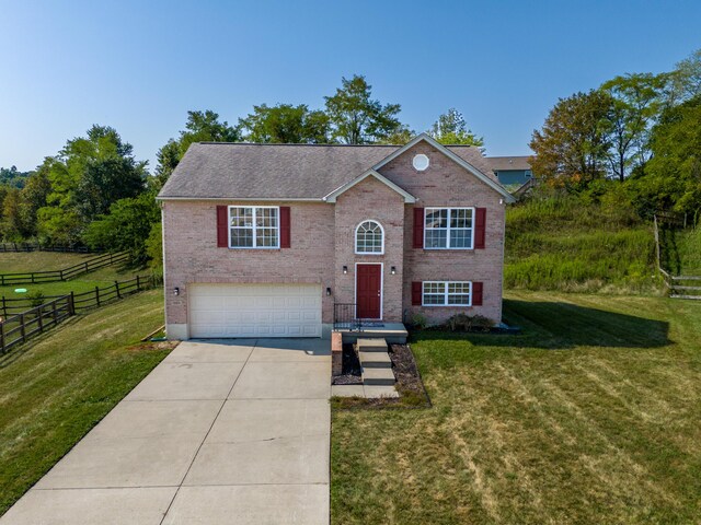 raised ranch with a front lawn and a garage