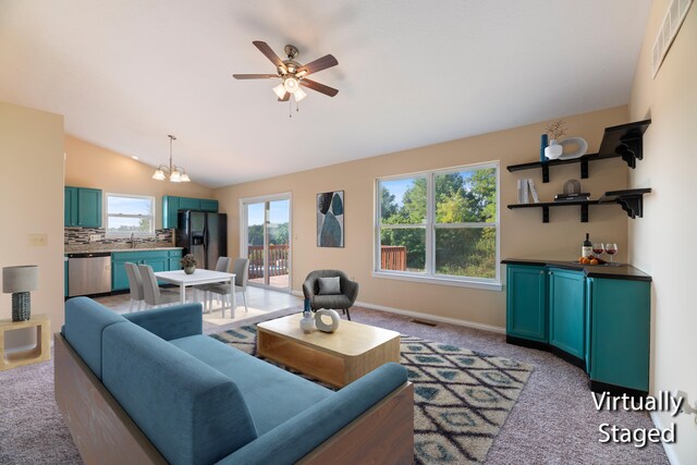 carpeted living room with ceiling fan with notable chandelier, lofted ceiling, and sink