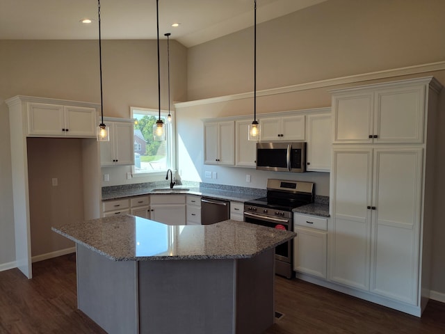 kitchen featuring sink, appliances with stainless steel finishes, a center island, light stone countertops, and dark hardwood / wood-style flooring