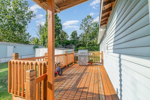 wooden terrace with an outdoor structure and a grill