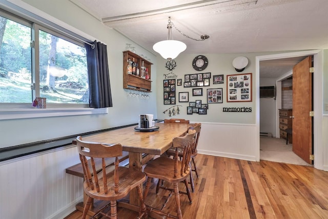 dining area with wood walls, hardwood / wood-style flooring, and a textured ceiling