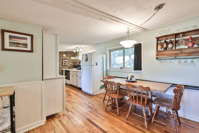 dining space with a textured ceiling and light hardwood / wood-style flooring