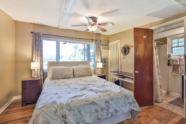 bedroom featuring multiple windows, an AC wall unit, ceiling fan, and dark hardwood / wood-style floors