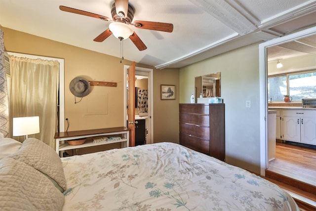 bedroom featuring wood finished floors, ensuite bath, and ceiling fan
