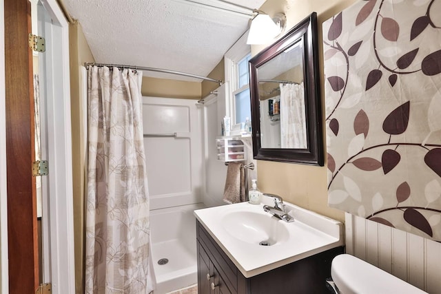 bathroom featuring vanity, toilet, walk in shower, and a textured ceiling