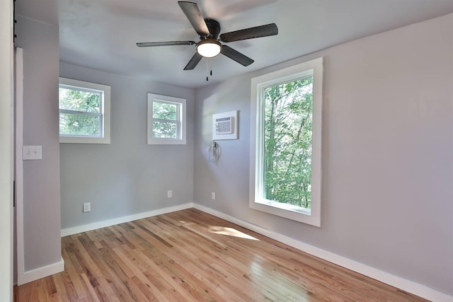 empty room featuring baseboards, a ceiling fan, wood finished floors, and a wall unit AC