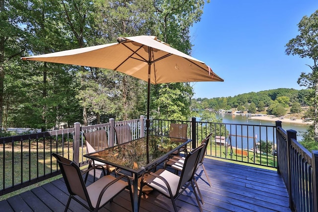 wooden deck featuring a wooded view, outdoor dining space, and a water view