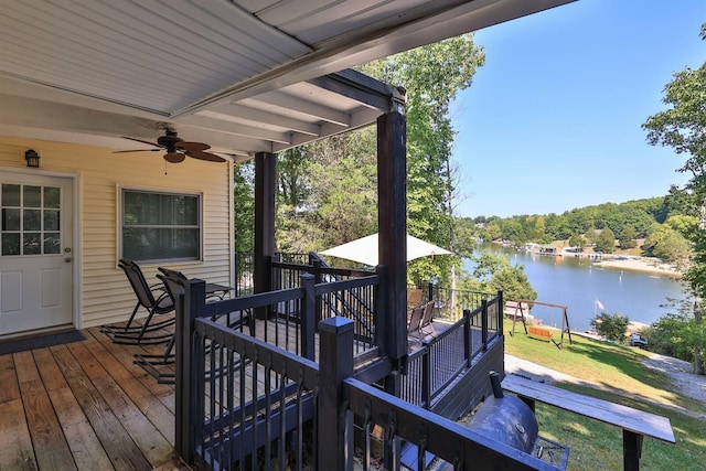 wooden terrace with a water view, a lawn, and ceiling fan