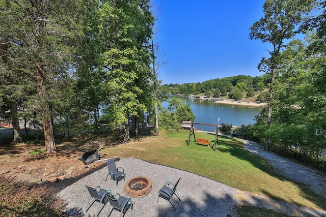 view of yard featuring a wooded view, a patio, a water view, and an outdoor fire pit