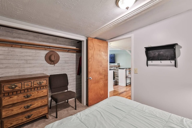 bedroom featuring a closet, wood-type flooring, wood walls, and a textured ceiling