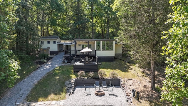 rear view of property featuring a fire pit, a lawn, and a wooden deck