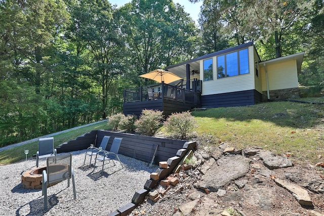 rear view of house featuring a wooden deck, a yard, a patio, and an outdoor fire pit