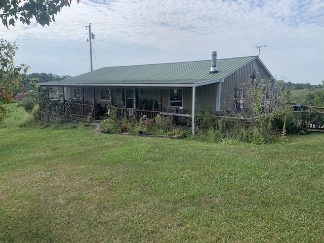 rear view of property featuring covered porch, a yard, and metal roof