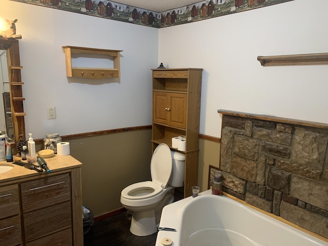 bathroom with toilet, wood finished floors, vanity, and a bath