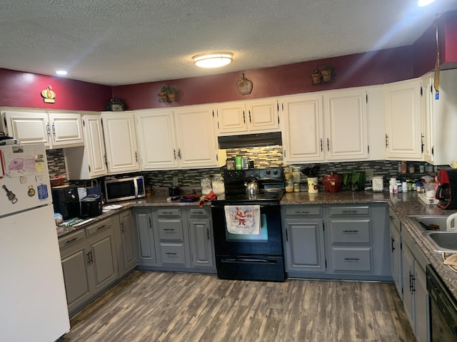 kitchen featuring gray cabinetry, dark wood-type flooring, white cabinets, under cabinet range hood, and black appliances