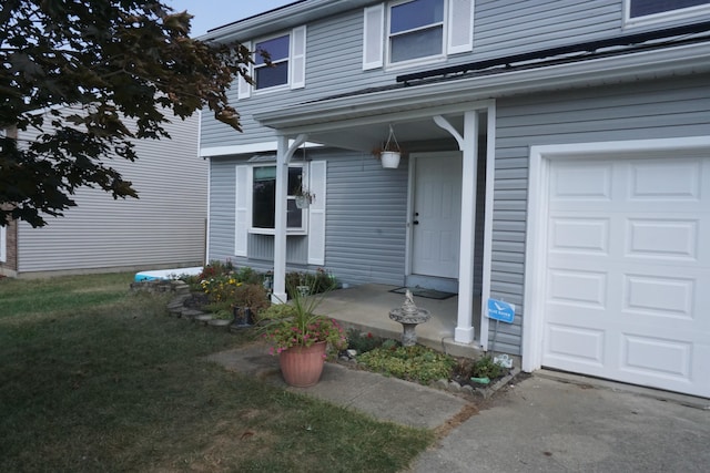 entrance to property featuring a lawn and a garage