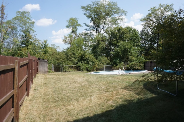 view of yard with a fenced in pool and a trampoline