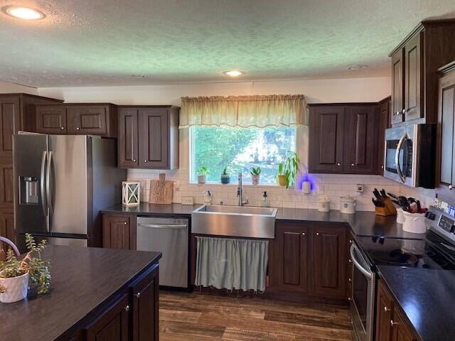 kitchen featuring dark hardwood / wood-style floors, sink, appliances with stainless steel finishes, dark brown cabinets, and a textured ceiling