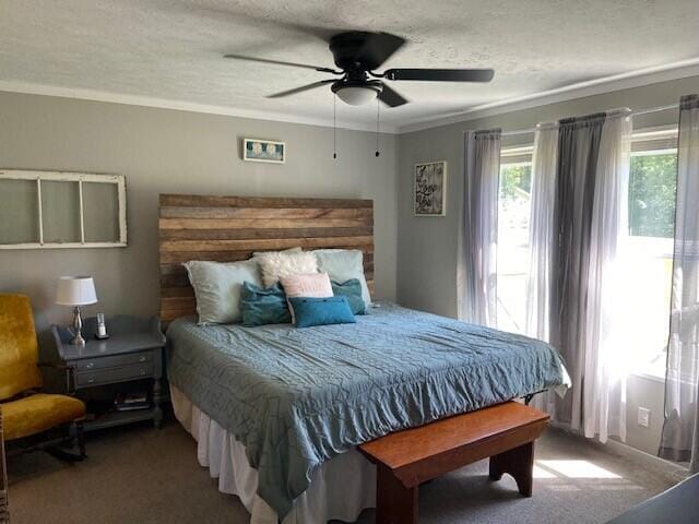 bedroom with ceiling fan, ornamental molding, a textured ceiling, and carpet flooring