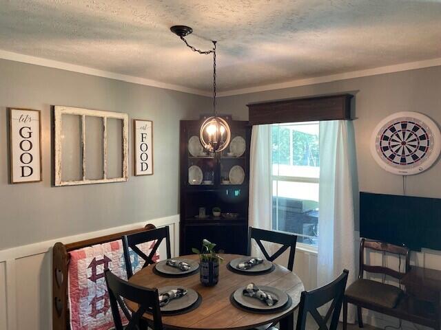 dining space featuring ornamental molding, a notable chandelier, and a textured ceiling