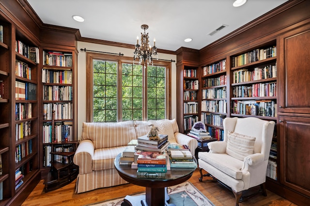 living area featuring a notable chandelier, ornamental molding, and dark wood-type flooring