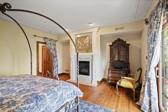 bedroom with light hardwood / wood-style flooring and a fireplace