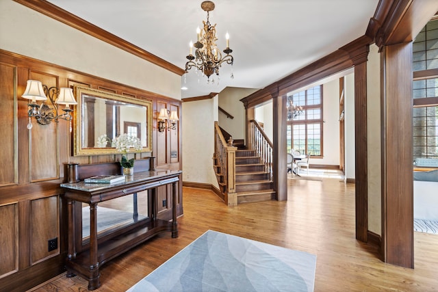 entryway with a notable chandelier, light hardwood / wood-style flooring, and crown molding