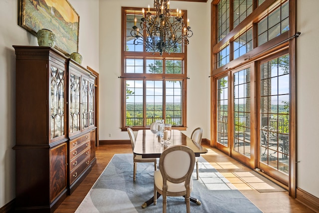 dining area featuring french doors, a chandelier, light hardwood / wood-style floors, and a high ceiling