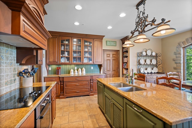 kitchen featuring premium range hood, an island with sink, sink, backsplash, and appliances with stainless steel finishes