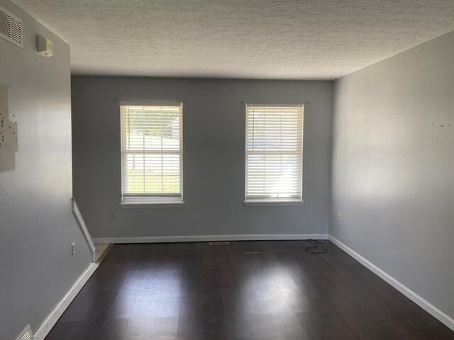 empty room featuring a textured ceiling and dark wood-type flooring