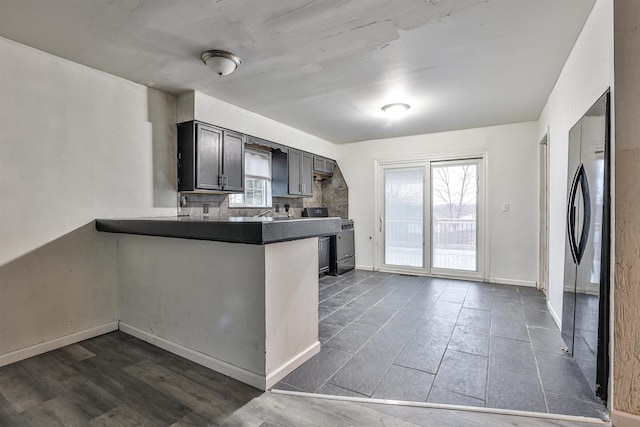 kitchen featuring kitchen peninsula, dark hardwood / wood-style flooring, tasteful backsplash, and black appliances