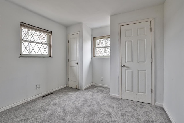 unfurnished bedroom with light colored carpet and multiple windows