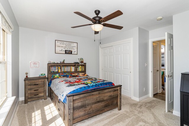 carpeted bedroom featuring ceiling fan and a closet