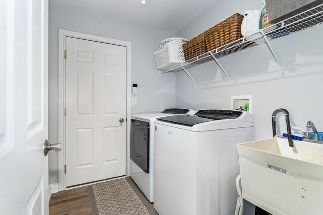 laundry room with washing machine and dryer, sink, and hardwood / wood-style flooring